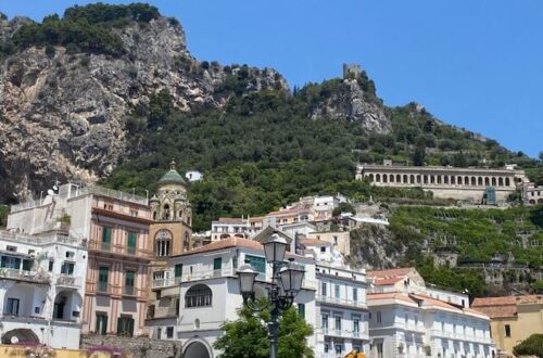 Amalfi town view from the port with the ancient towers peeking from the top of the mountain behind the town