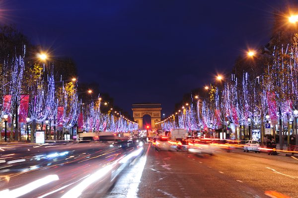 Arc du Triomphe in Paris at night with lights on the trees