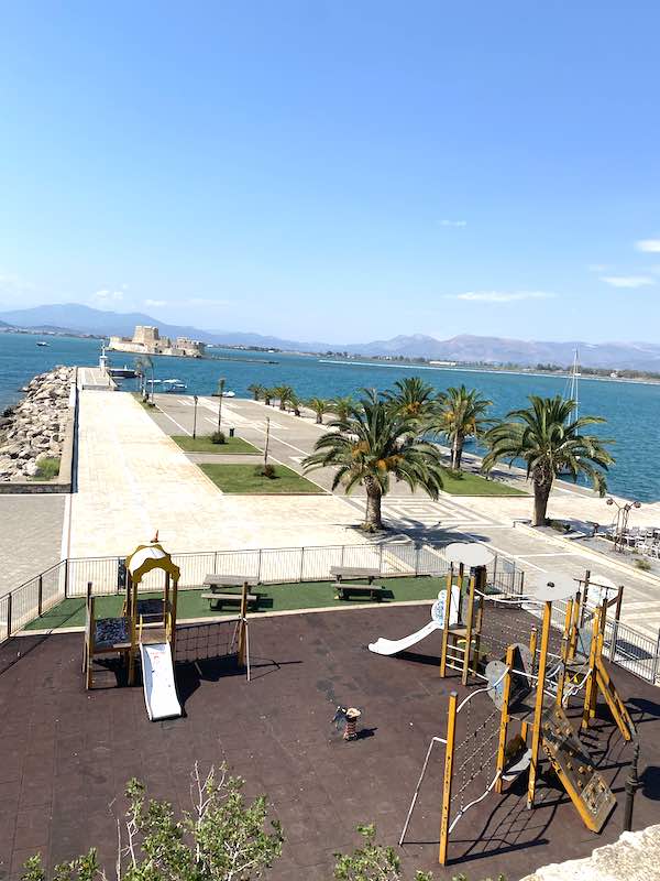 Children playground in Nafplio, from the upper part of town, with slides and climbing frames, and a sea fortress in the background