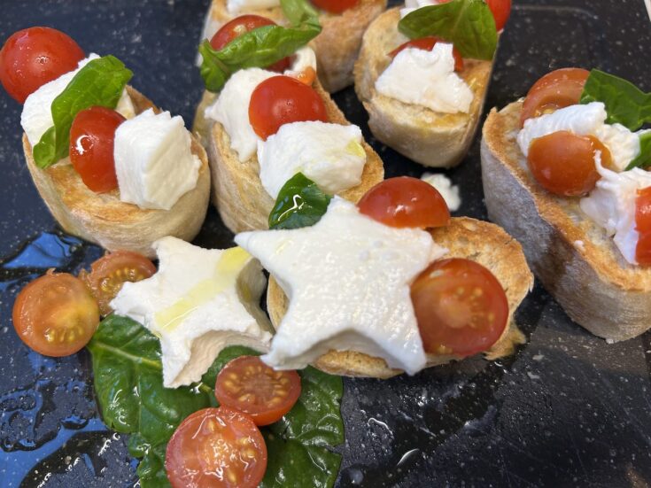 christmas bruschetta on dark cutting board, with star shaped mozzarella