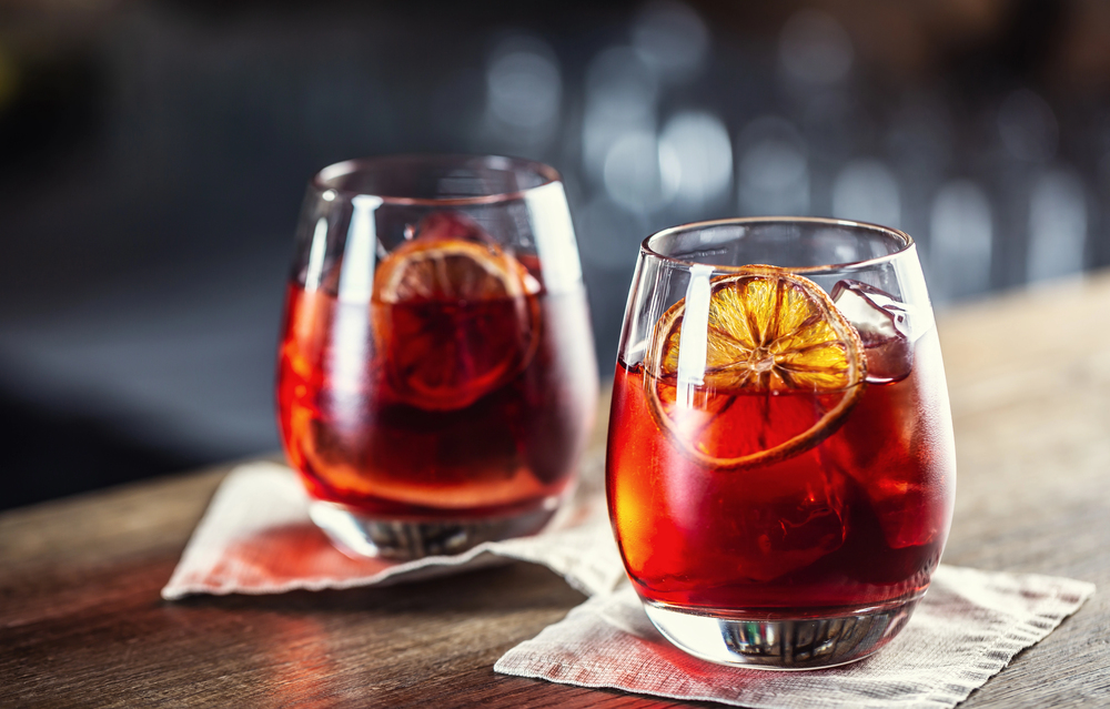 two glasses of red negroni cocktail with dried citrus slice