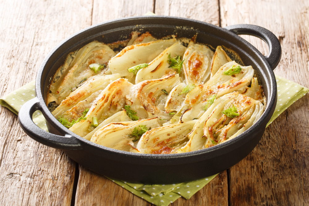 Fennel gratin in black skillet on wooden table