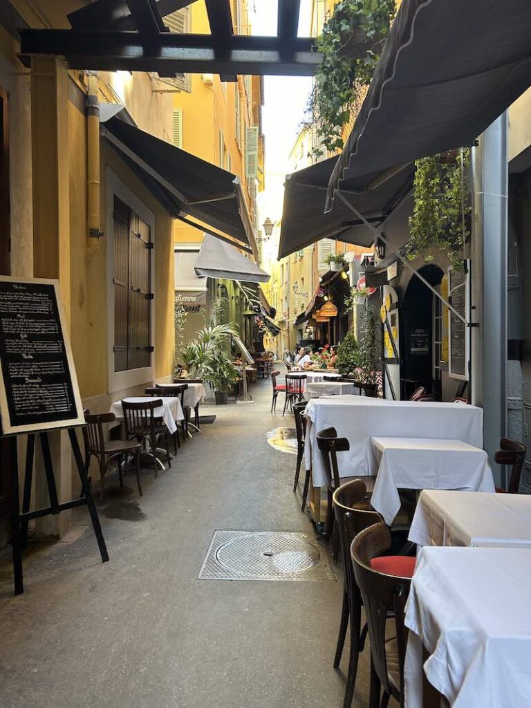 Road in old city Nice with restaurant tables
